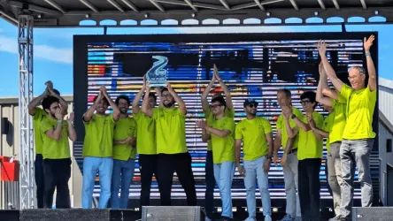 Group of people wearing bright green t-shirts on a stage holding up a first-place trophy.